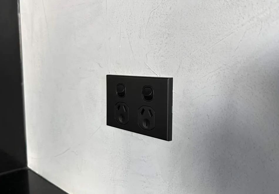 Matte black double power point and switches installed on a textured wall