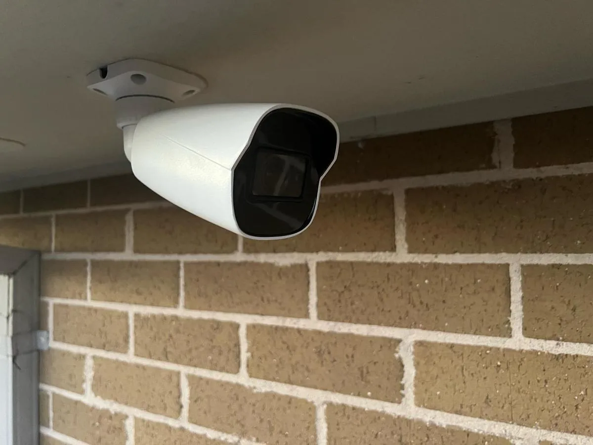 Outdoor CCTV security camera mounted under a soffit against a brick wall
