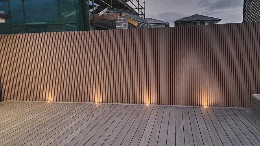 Outdoor deck and fence with warm uplighting at dusk