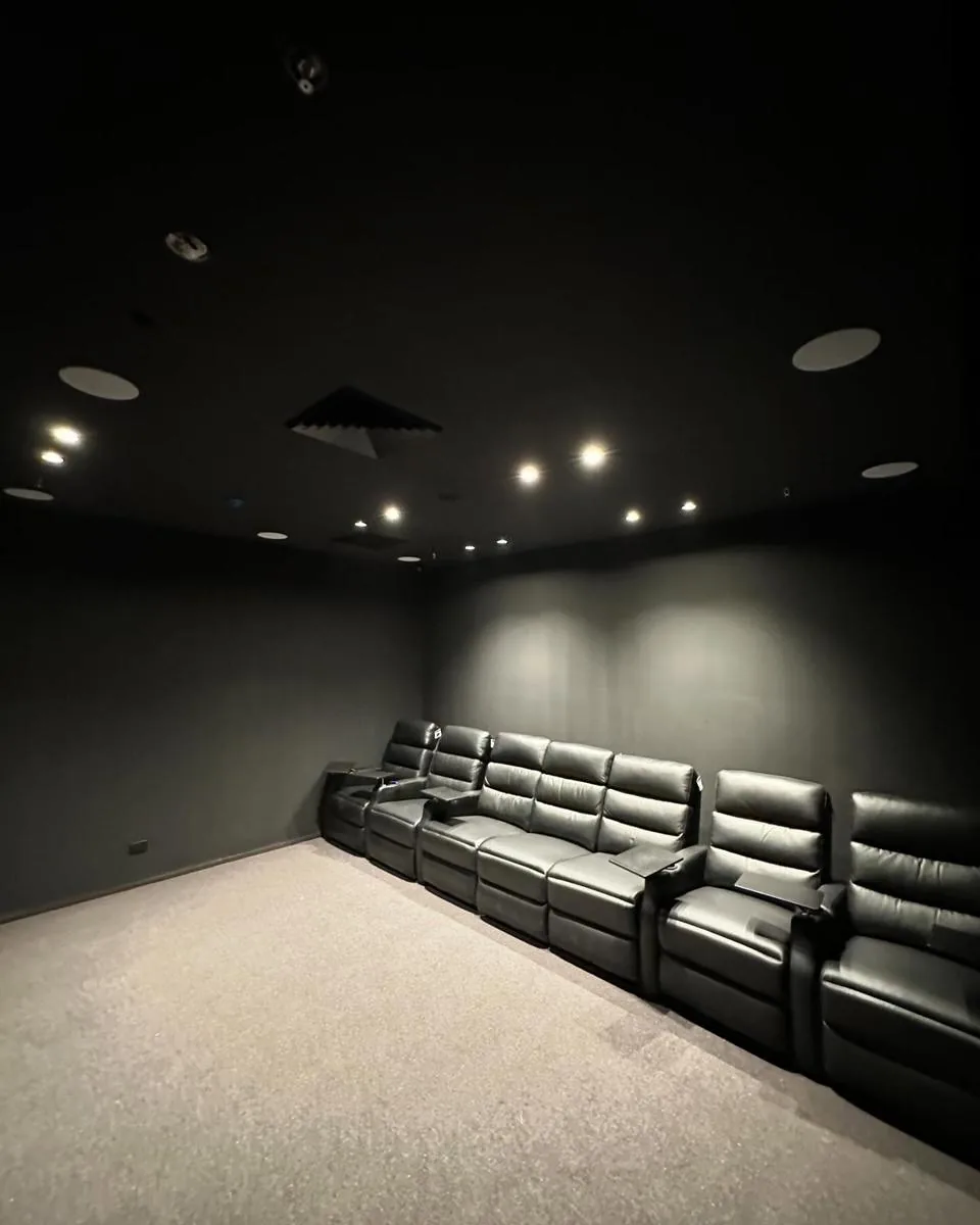 Dark home theatre room with recessed lighting and cinema seating