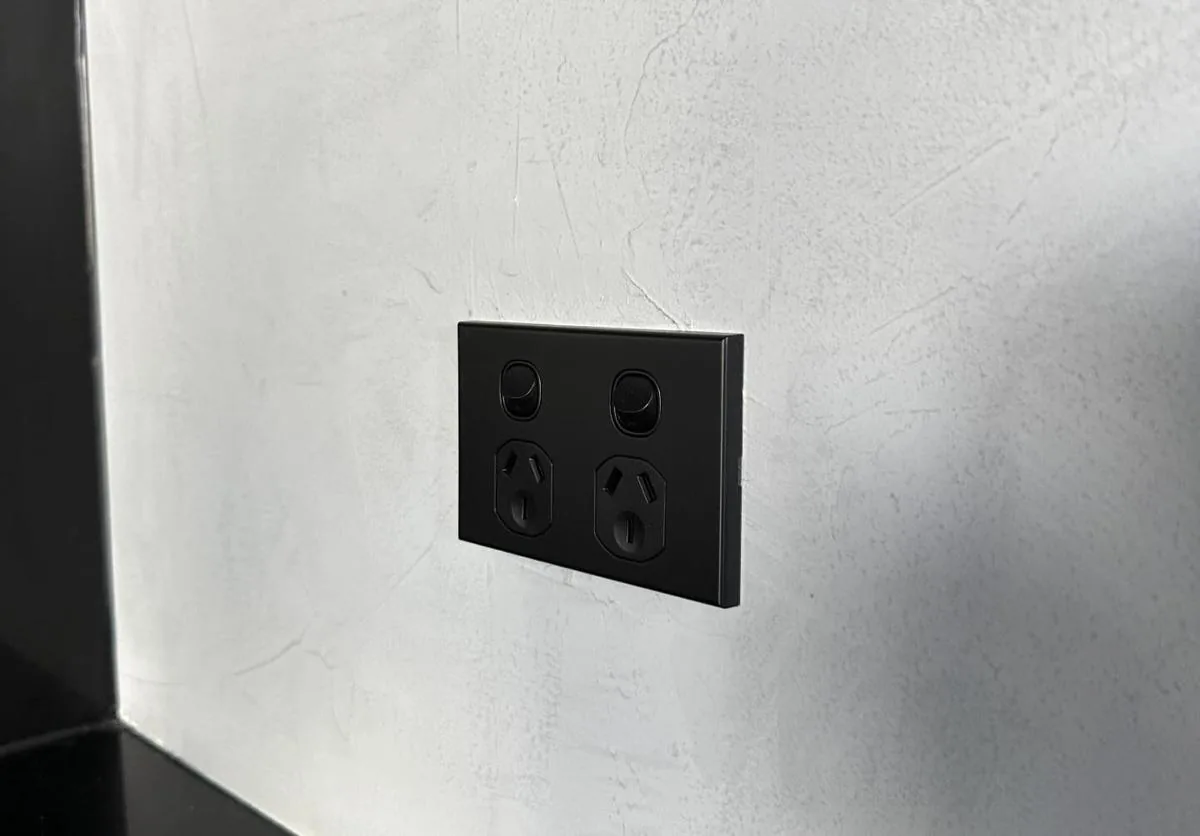 Matte black double power point and switches installed on a textured wall